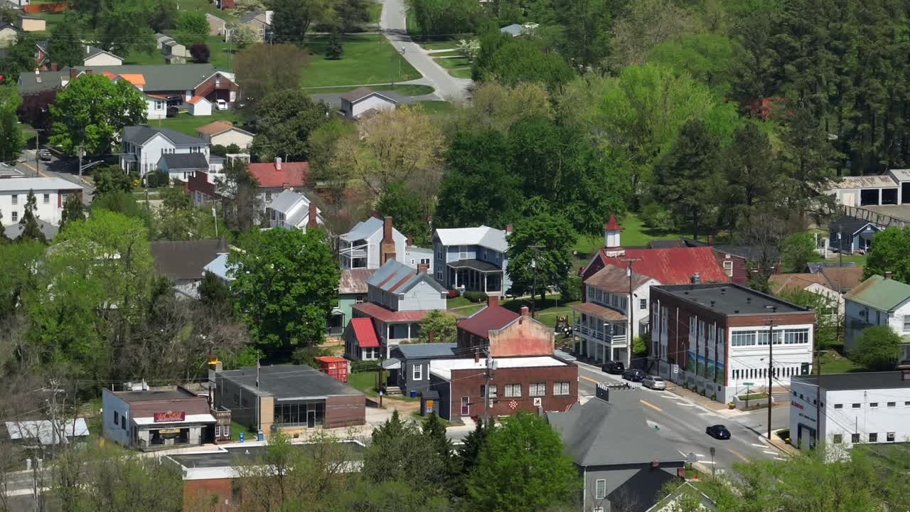 Cars on street of small american town with church and colored houses on hillside. Sunny day in spring Season. Aerial wide shot. Virginia, USA.