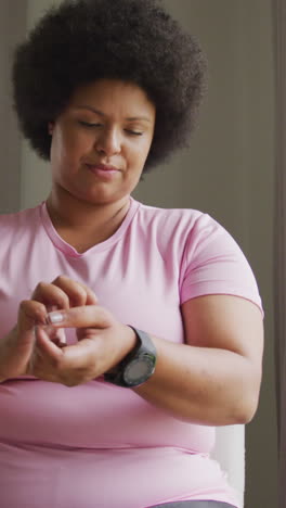 video of plus size african american woman in sport clothes putting on smartwatch