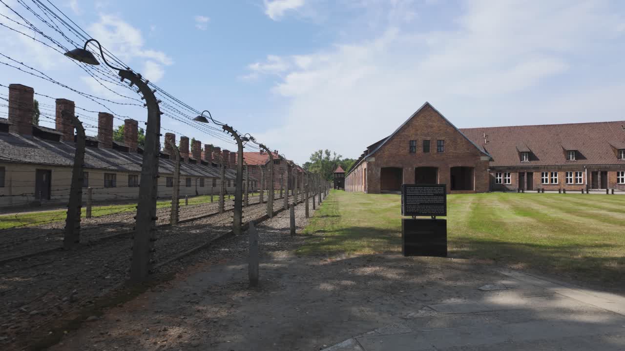Historic Auschwitz concentration camp in Poland under a bright sky with barbed wire and buildings
