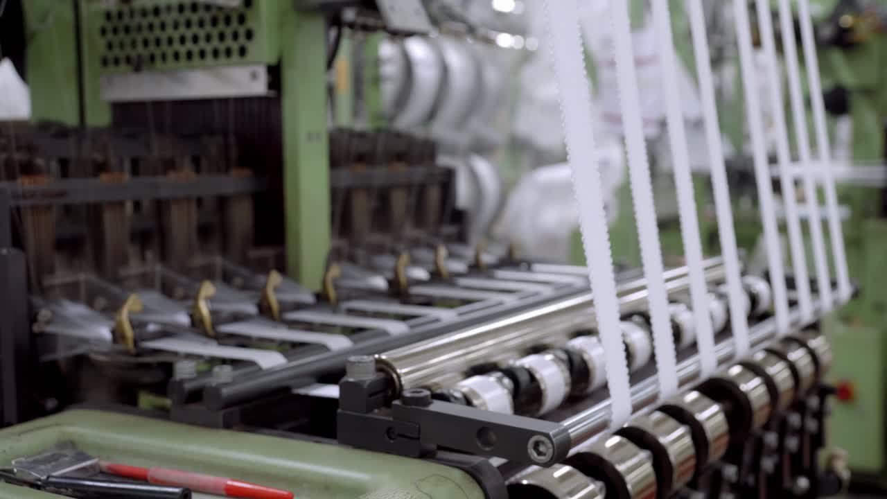 Timelapse-visning af maskiner, der fremstiller bånd inde i en fabrik, gentagen industriel produktions arbejdsgange