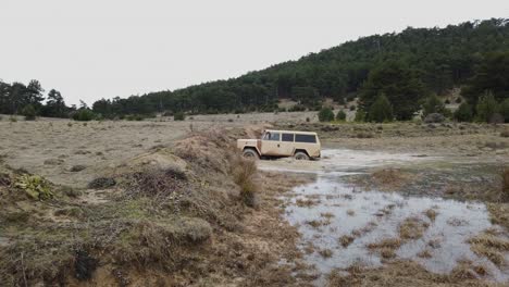 viejo coche todoterreno de color crema cruzando un charco