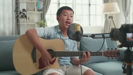 teenager singing and playing acoustic guitar at home