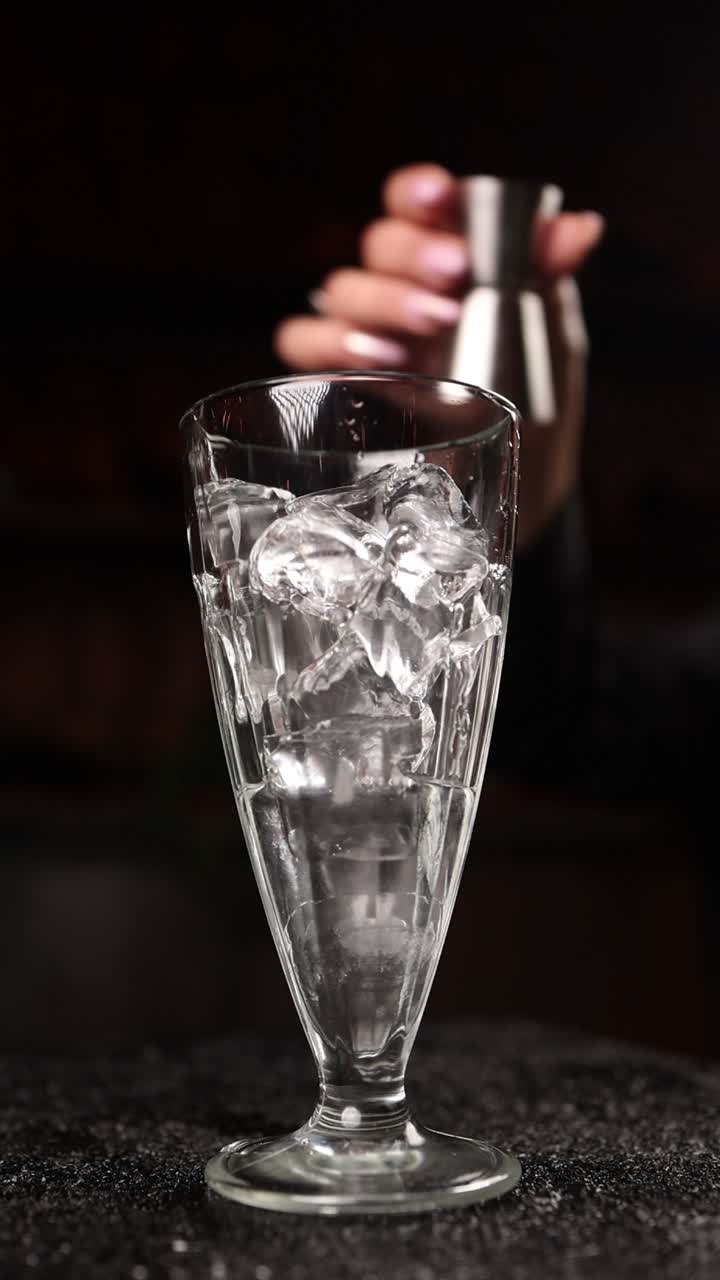 Barman che versa liquore in un bicchiere pieno di ghiaccio