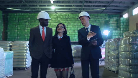 Business people in hard hats inspecting a warehouse with goods