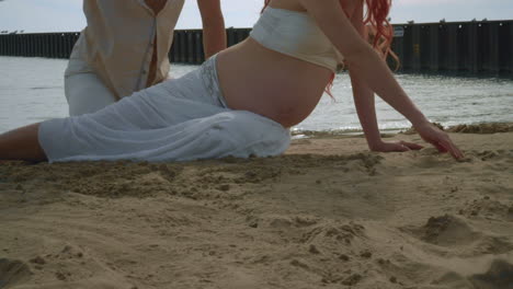 pregnant couple drawing on beach sand. love couple relaxing on beach