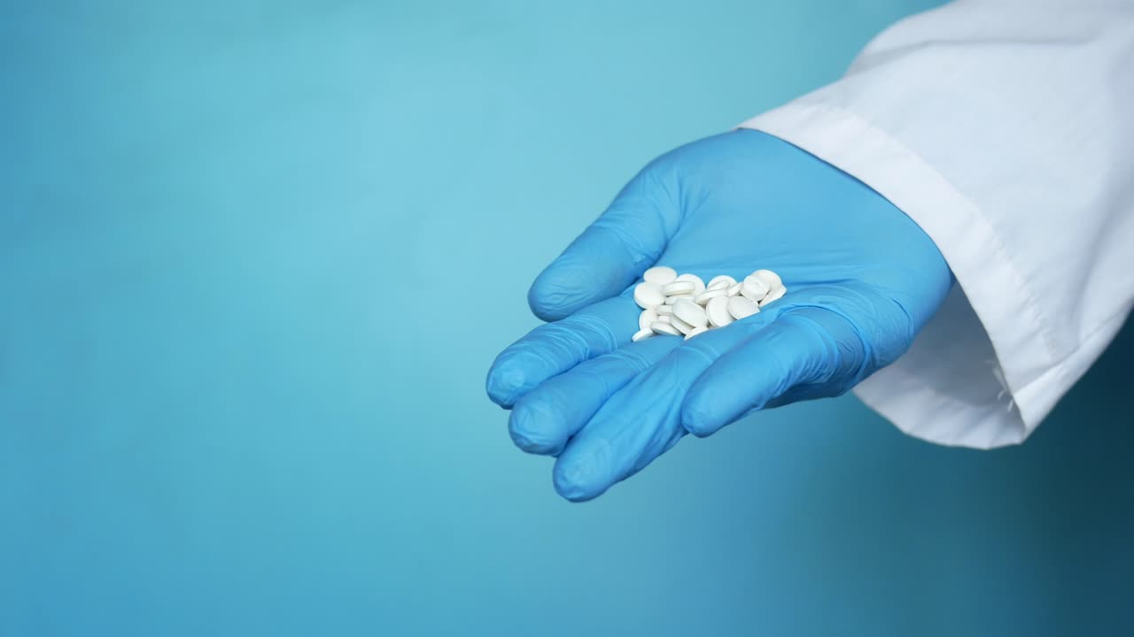 Médico sosteniendo pastillas con guantes azules