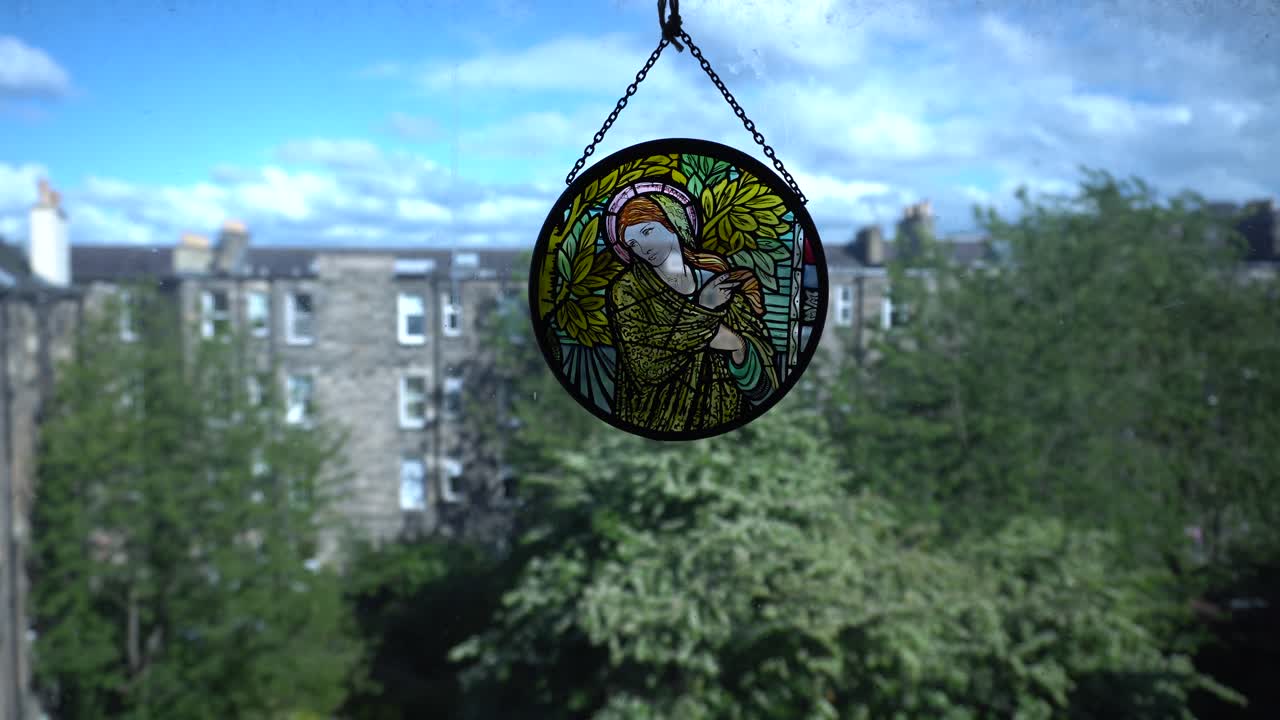 colgante de vidrio manchado colgado en la ventana con vista a un patio trasero