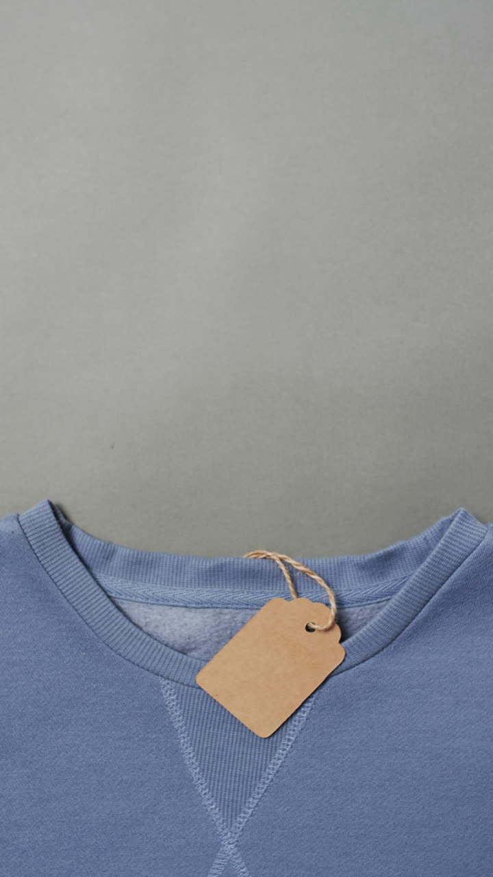 Vertical video of blue t shirt with tag and copy space on grey background