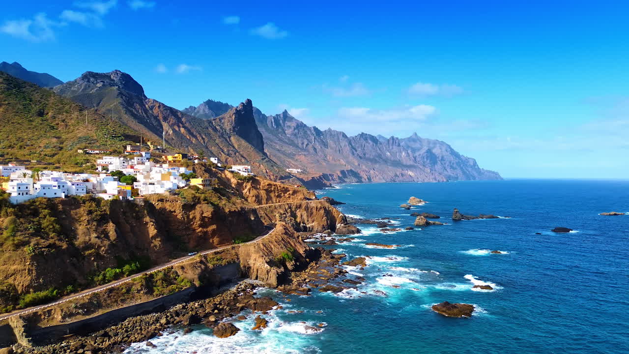Flight over the blue waterscape of the Atlantic Ocean at the rocky coast of Tenerife, the Canary Islands, Spain. View on the numerous villas located on the cliffs of the shore