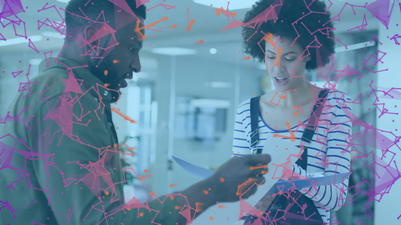 Male colleague pointing at documents, female colleague reading papers, business network graphics