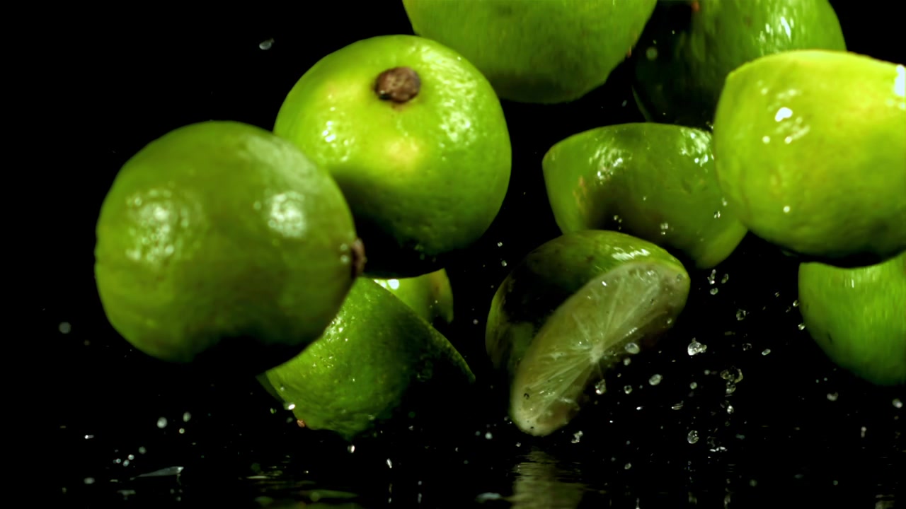Rallentatore di lime freschi e metà che schizzano nell'acqua