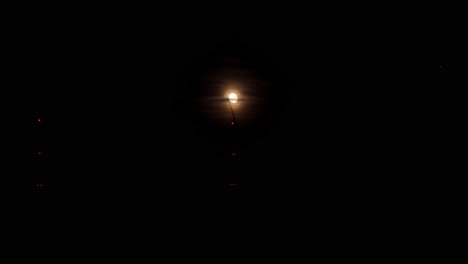 la luz distante de la luna llena ilumina las hélices giratorias de la turbina eólica