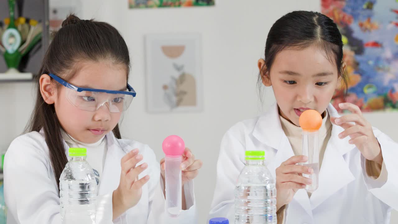 To unge asiatiske piger i laboratoriekåber udfører et fysikeksperiment ved hjælp af lufttryk