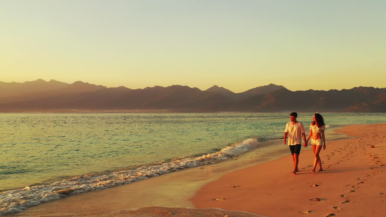 Young couple enjoying summer vacation on tranquil exotic beach on tropical islands surrounded by beautiful sea and mountains horizon