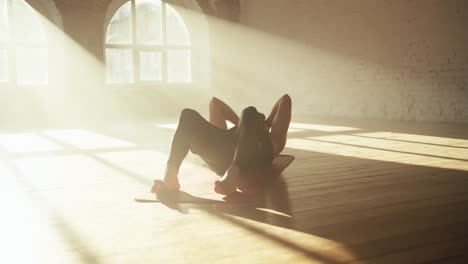 a man in a black sports summer uniform goes in for sports and does exercises for pumping the abdominal muscles in a sunny brick