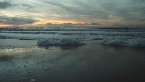 foam washed up on the beach of sylt with the sunset in the background
