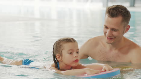 father teaching daughter to swim