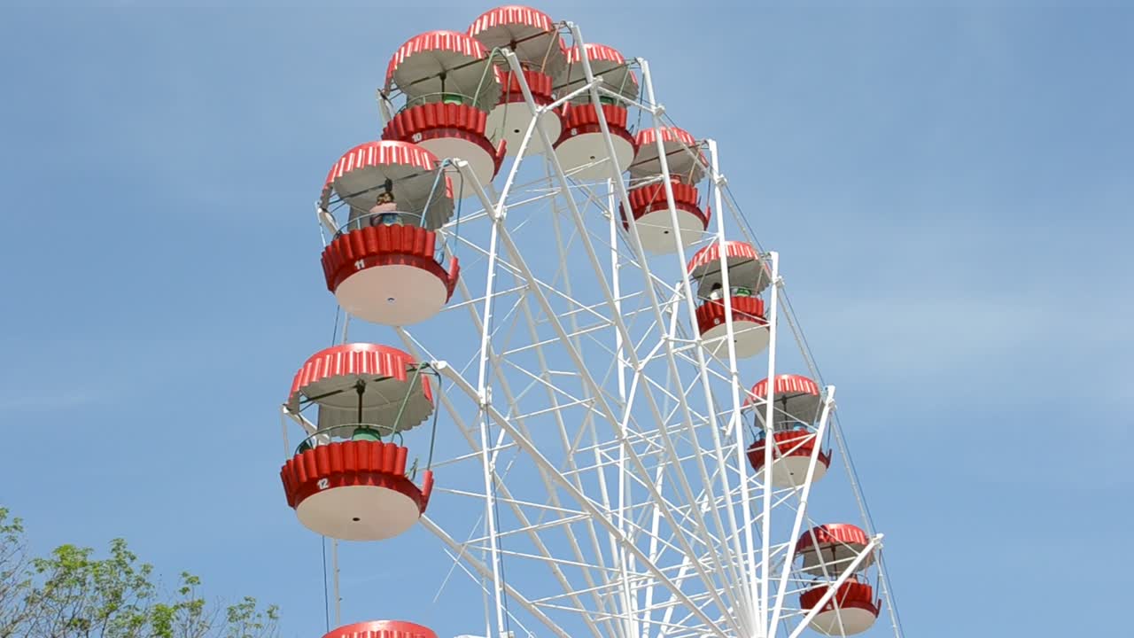 big wheel with multicolored cabins in amusement park