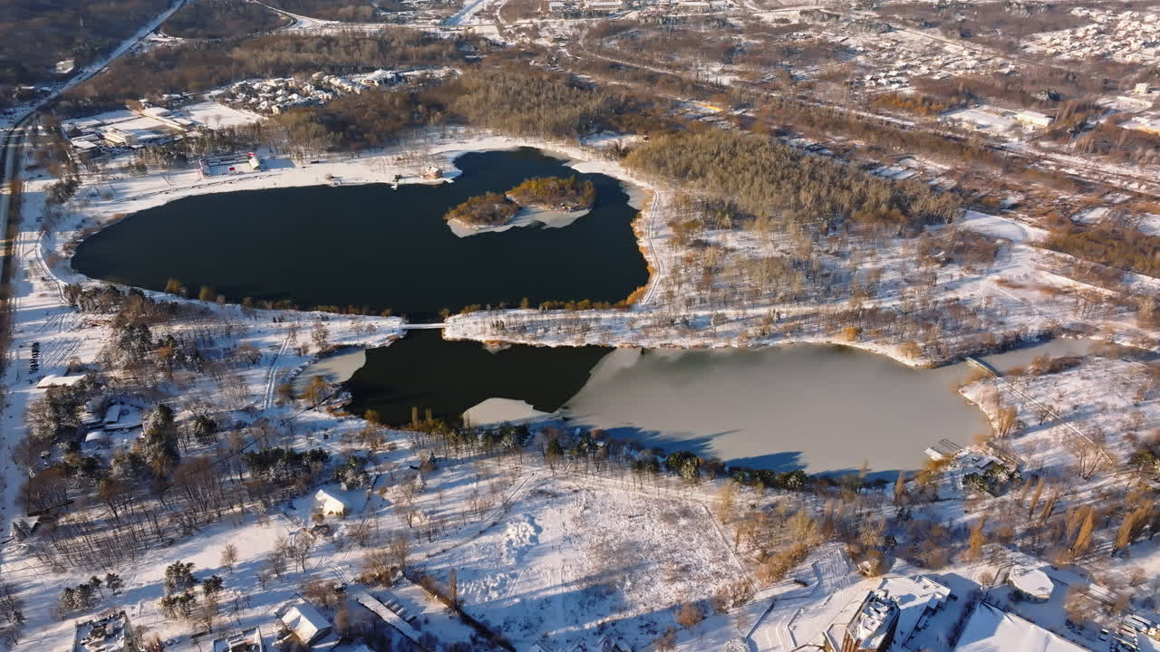 Aerial drone view of a lake in winter at sunrise. The ground covered by snow in Chisinau, Moldova