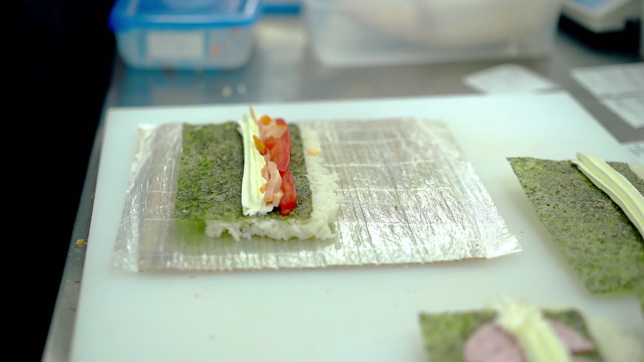 cozinheiro prepara rolos japoneses com pepino búlgaro pepino salsicha fumada