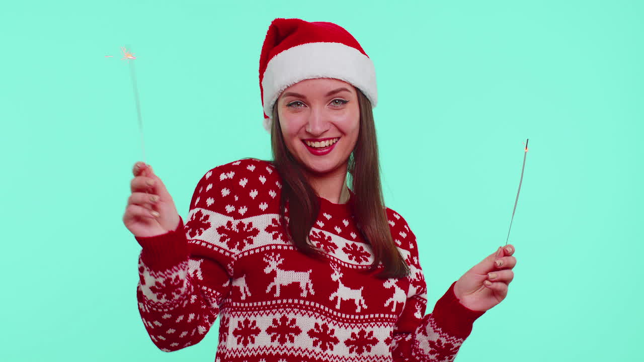 Lovely girl in Christmas Santa sweater dancing with bengal sparklers fireworks ligts, congratulation