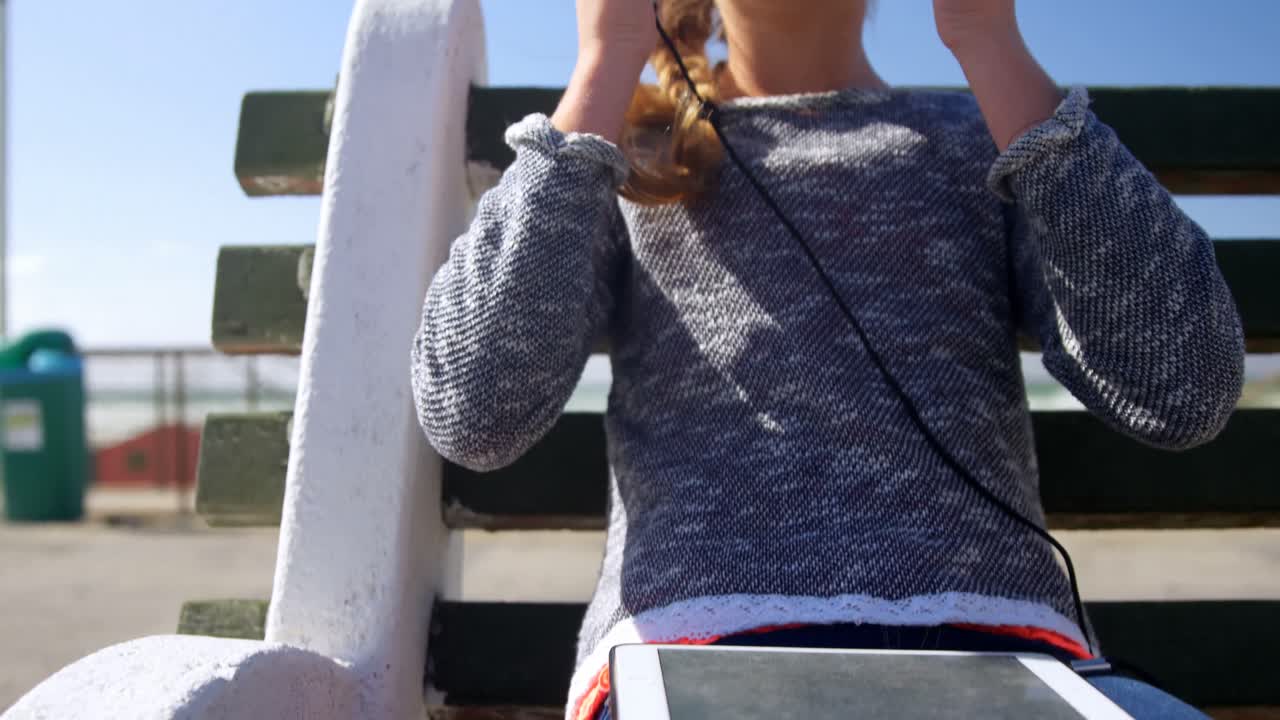 해변 4k에서 헤드폰으로 음악을 듣는 소녀