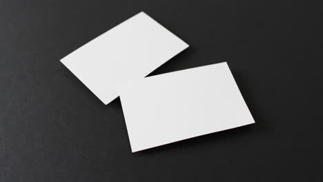 primer plano de tarjetas de visita blancas en blanco sobre fondo negro, espacio de copia, cámara lenta