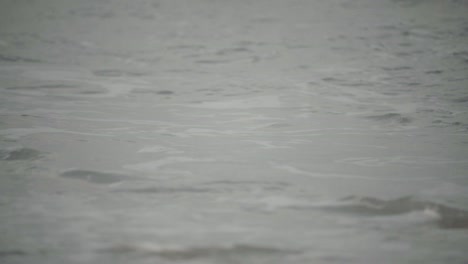 Primer-Plano,-La-Marea-Del-Océano-Chocando-Contra-La-Orilla-De-La-Playa-En-Un-Día-Nublado-Sombrío