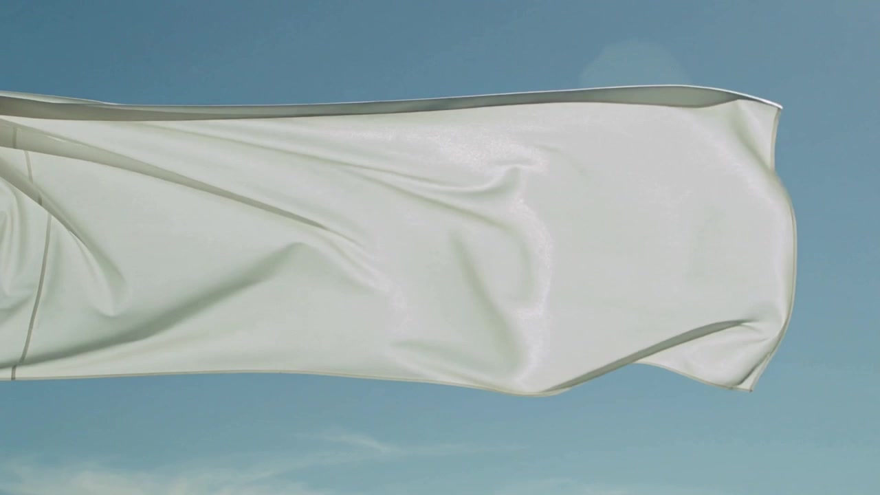 Bandera blanca ondeando reaccionando al viento racheado a través del cielo azul, revelando el dobladillo y un destello de lente.