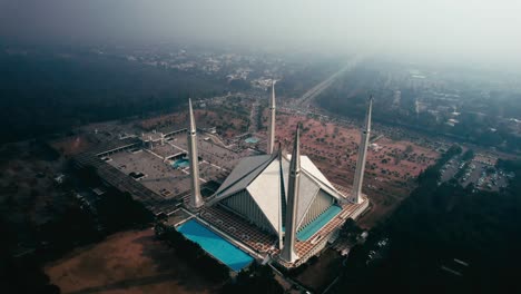 Mezquita-Faisal-En-Islamabad-Con-Paisaje-Circundante-A-La-Luz-Del-Día,-Toma-Aérea