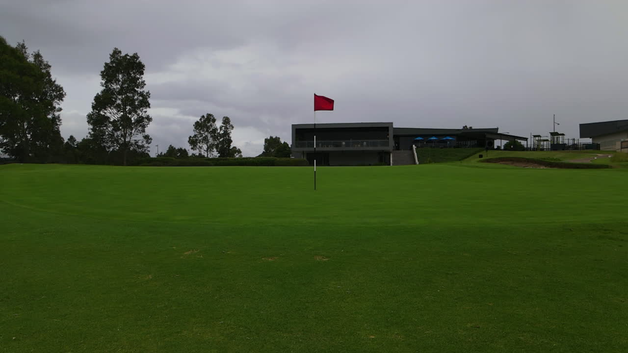 클럽 하우스 옆 골프장 18번 홀의 잘 다듬어진 그린에 있는 빨간색 골프 폴 플래그