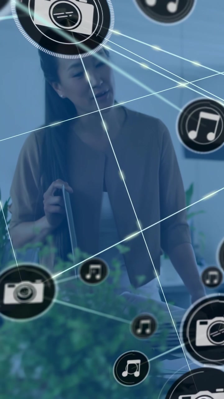 Dikey video: Ofis çalışanı kadın tablete dokunuyor, medya için üst üste binen kamera veya müzik simgelerini başlatıyor.