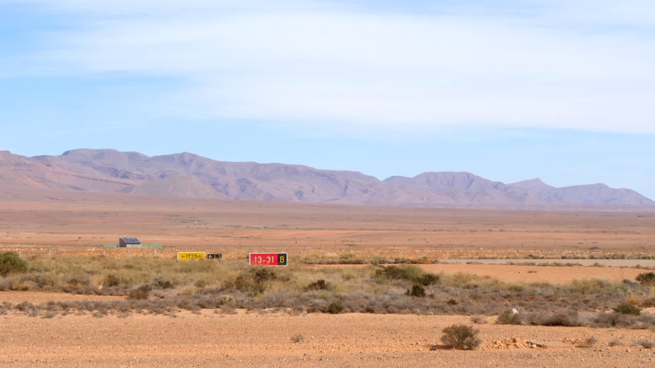 사막의 조용한 공항, 배경의 높은 산에 있는 공항 표지판과 활주로 지정자의 넓은 사진