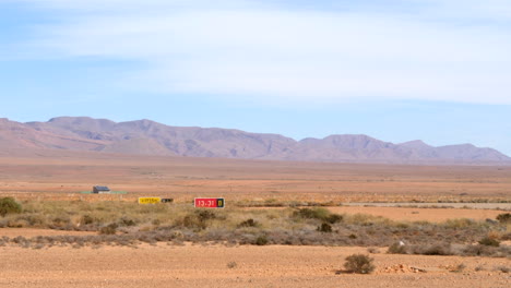 Wide-shot-of-airport-signs-and-runway-designators-on-a-quiet-airport-in-the-desert,-high-mountains-in-the-background