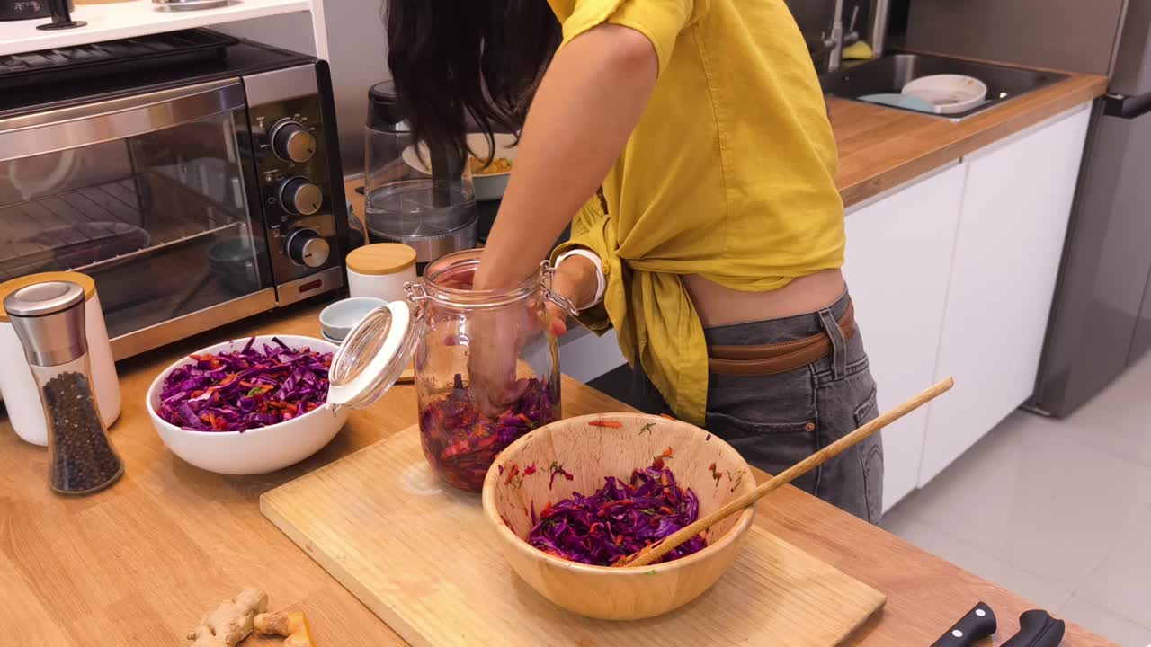 mujer fermentando repollo rojo en la cocina
