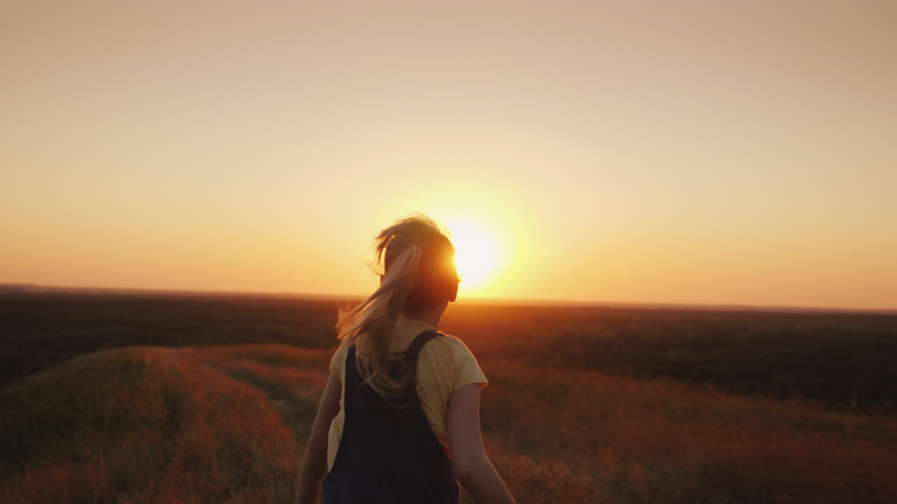 un niño despreocupado con una mochila detrás de él corre hacia el sol, las vacaciones de verano y el concepto de libertad