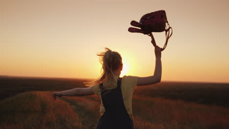 a carefree child with a knapsack behind him runs towards the sun summer holidays and freedom concept