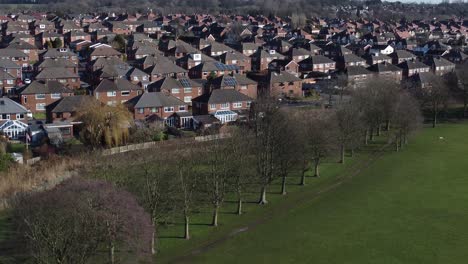 Typical-Suburban-village-residential-Bradford-neighbourhood-property-rooftops-aerial-view-descending-to-tree-line