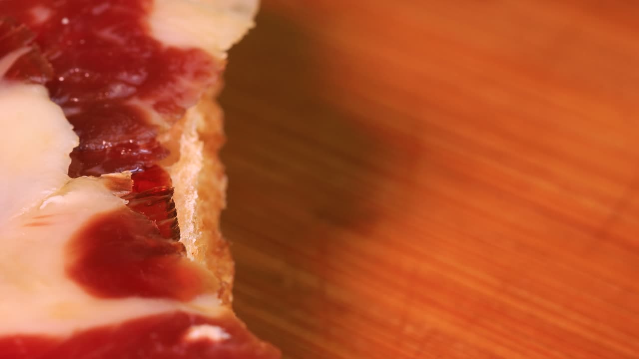 loncha de jamón curado muy graso encima del pan, tiro macro