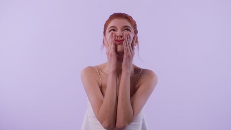 a young woman rubs face cream between her hands and applies it smoothly across her face while smiling calmly.