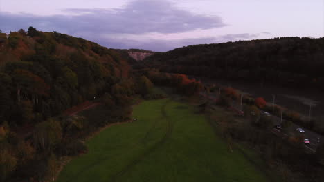 Drone-shot,-moving-backwards-whilst-ascending-to-reveal-Bennetts-Patch-nature-reserve,-River-avon,-Avon-Gorge---A4-Portway-during-sunset-on-autumn-evening