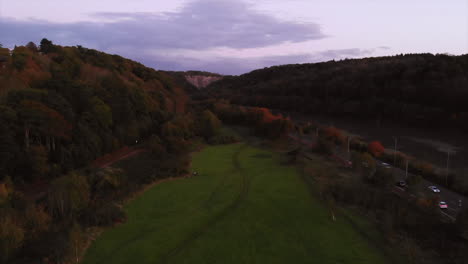 drone shot, moving backwards whilst ascending to reveal bennetts patch nature reserve, river avon, avon gorge - a4 portway during sunset on autumn evening