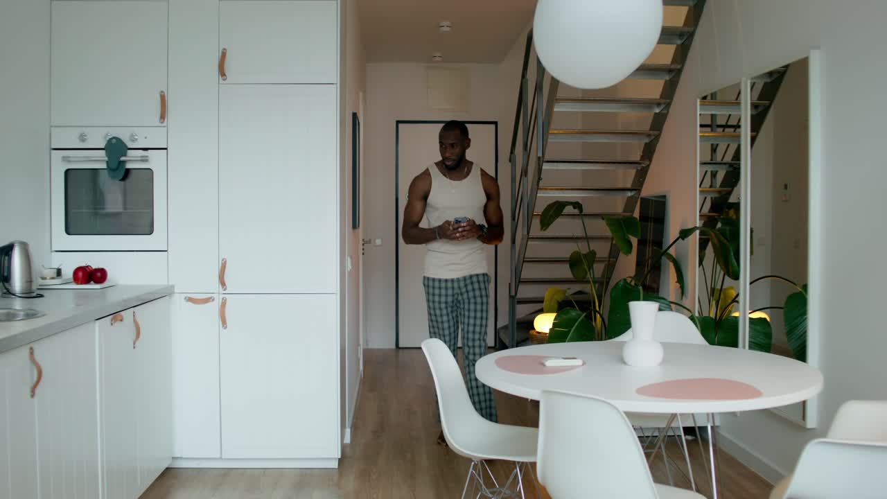 hombre en pijama usando teléfono en una cocina moderna