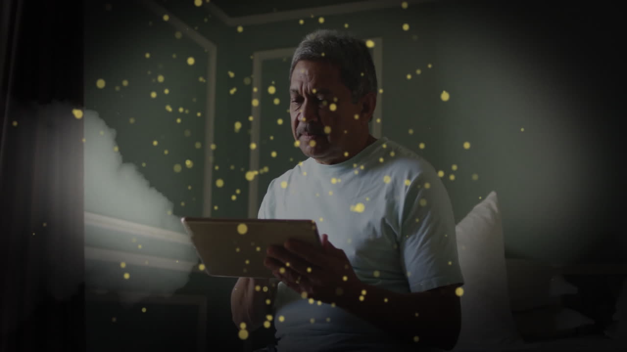 Senior man using tablet in bedroom, with glowing particles floating around showing technology theme