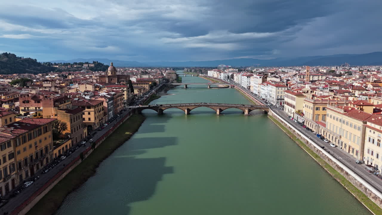 Florence cityscape with Arno River and historic bridges under a dramatic sky