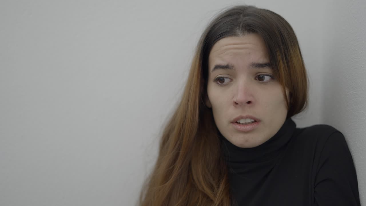Woman leaning against a wall looking troubled
