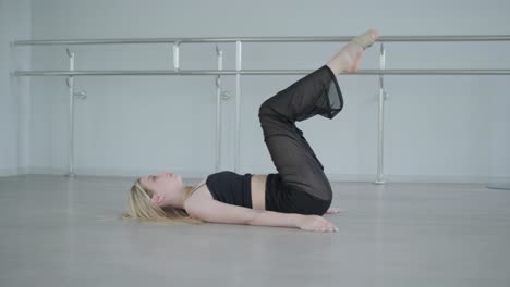 fit girl in black clothes performing contemporary. female dancer shows flowing motions, body and hands waves at white room. modern ballet dance choreography. young woman is moving smoothly