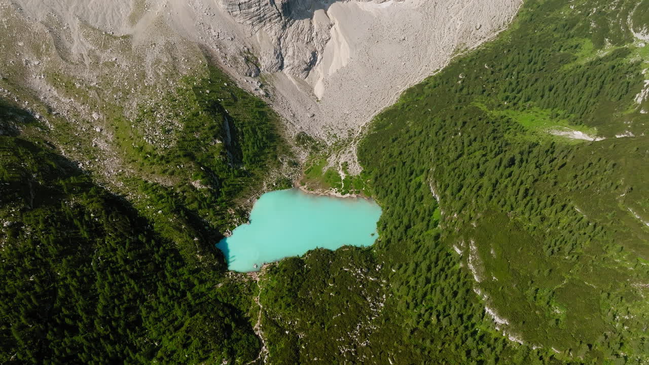 Drönarvy över Sorapis-sjön inramad av taggiga Dolomitklippor och skogsklädda sluttningar