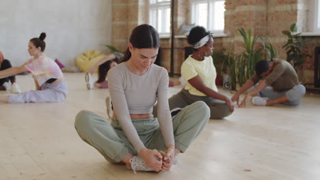 woman doing butterfly stretch in dance studio