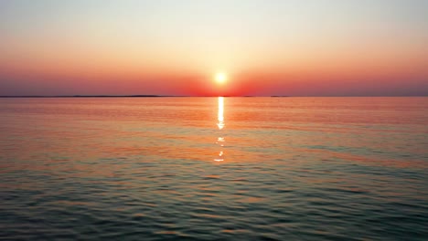 Beautiful-Ocean-Sunset-with-Bright-Glowing-Sun-Casting-Colorful-Red,-Orange,-Purple-and-Yellow-Reflections-Over-Peaceful-Rippling-Waves-of-the-Sea-with-Gorgeous-Sky-and-Water